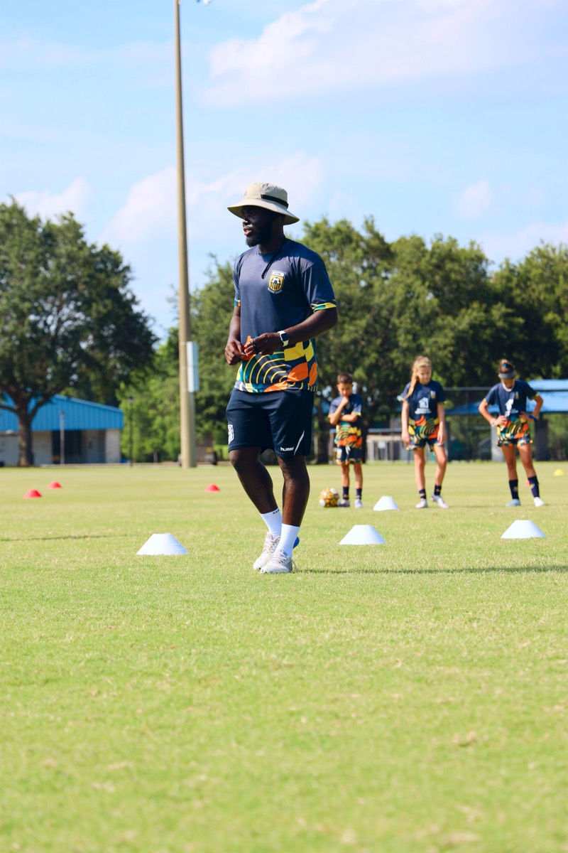 Coach Melvin on the training field with cones