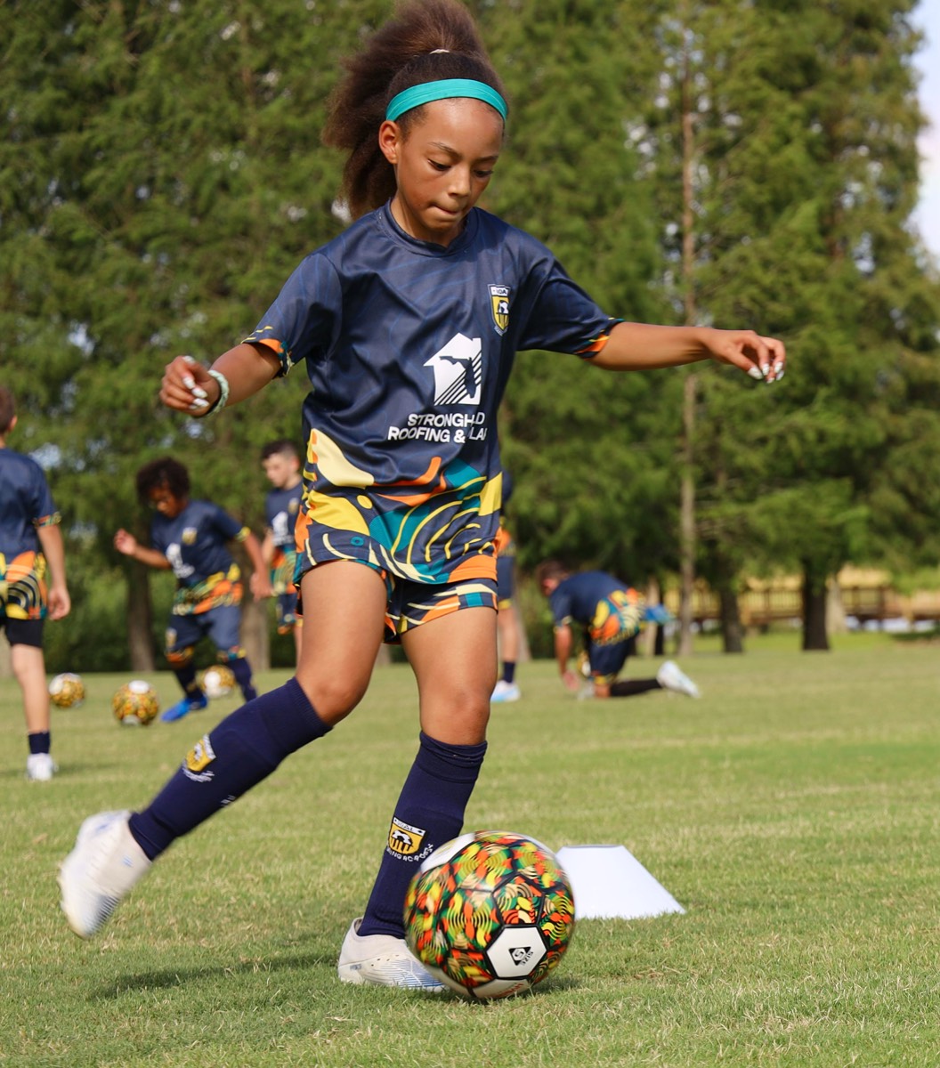 Young athlete kicking the ball during training